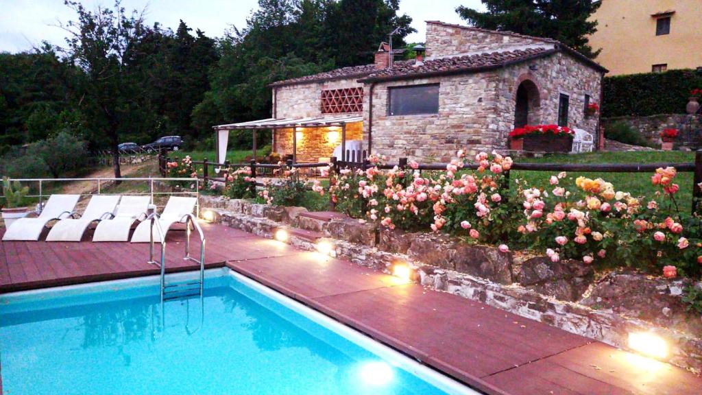 a swimming pool in front of a house with flowers at Il Poggio al Sole in Fiesole