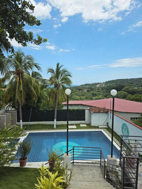 a swimming pool in a yard with palm trees at Habitaciones Casa Cuscatlan in Tamanique