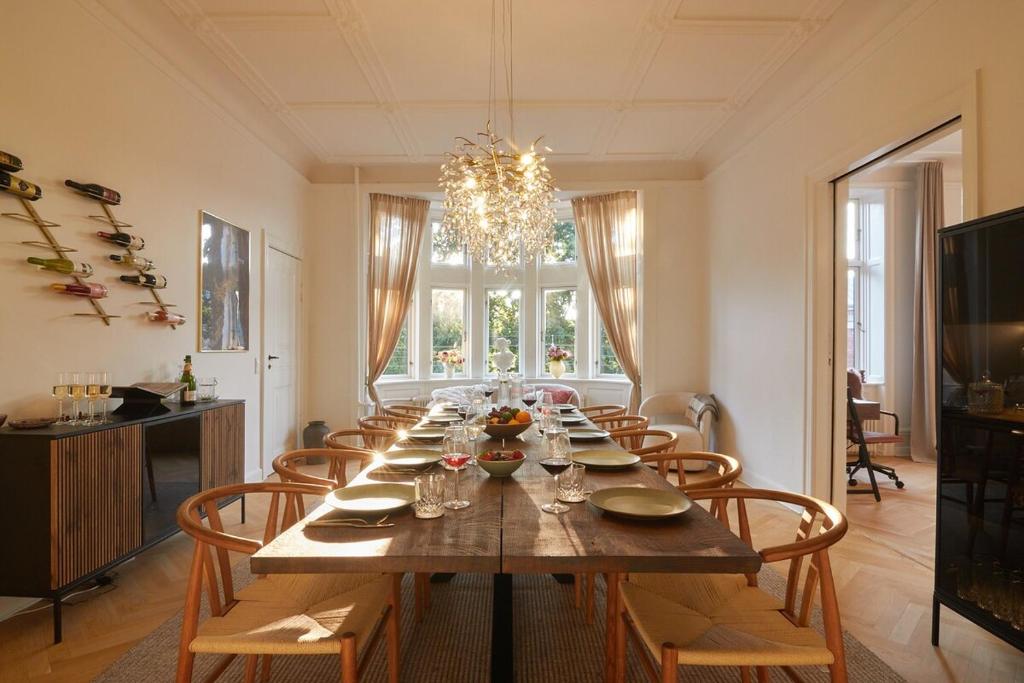 Un comedor con una mesa larga y sillas. en Huge Royal Luxury Apt with Private Balcony, en Copenhague