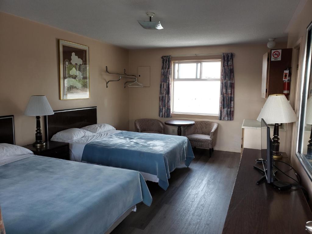 una camera d'albergo con due letti e una finestra di Georgian Inn Motel a Wasaga Beach