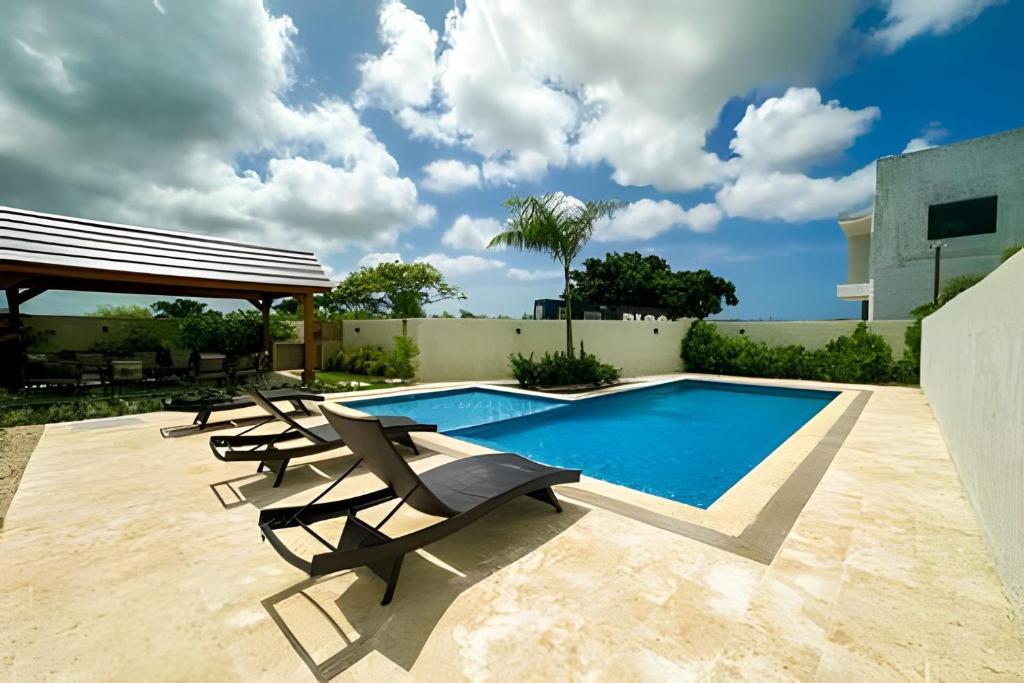 a swimming pool with lounge chairs next to a house at Villa familiar en Punta Cana! Piscina Climatizada in Punta Cana