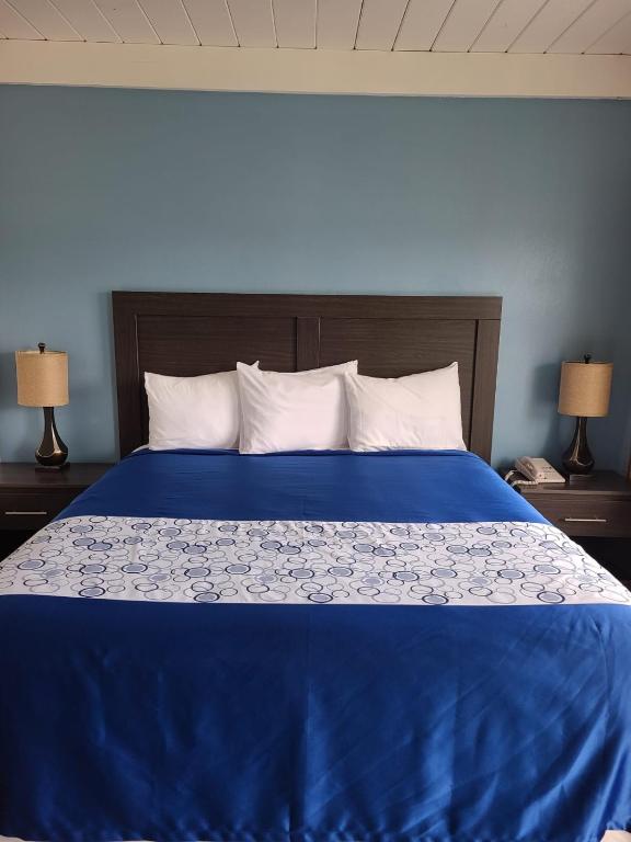 a bedroom with a blue bed with two lamps at All Seasons Lodge in South San Francisco