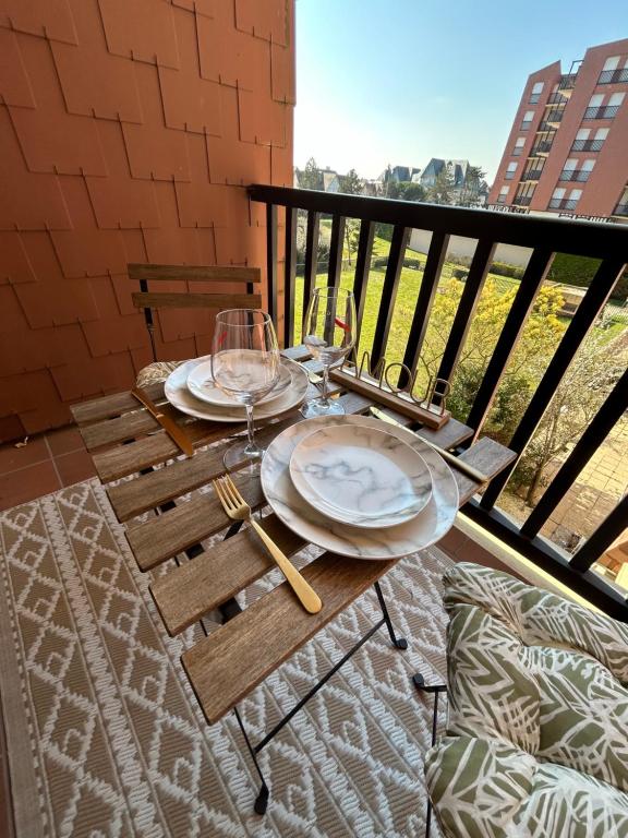 une table avec des verres et des assiettes sur un balcon dans l'établissement La Suite Émeraude - Cosy, chic et bord de mer, à Cabourg