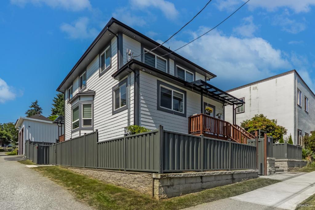 a house with a fence on a street at Budget Friendly 2 Bedroom Suite - Save on Weekly and Monthly Stays! in New Westminster