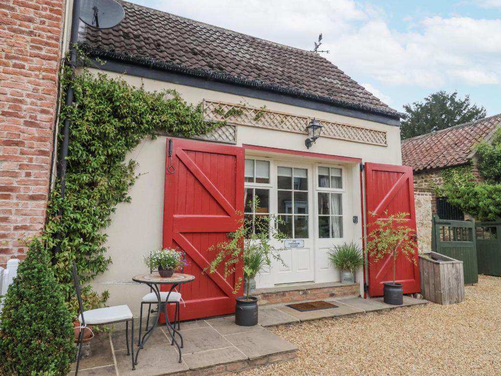 a cottage with red doors and a table and chairs at The Farmhouse Kitchen in Ripon