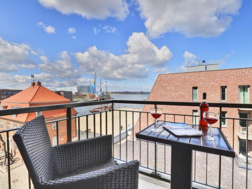 a balcony with a table and two glasses of wine at Ohlerich Speicher App_ 20 in Wismar