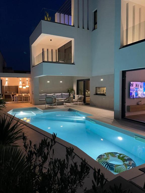 a swimming pool in front of a house at night at Villa Burin in Murter