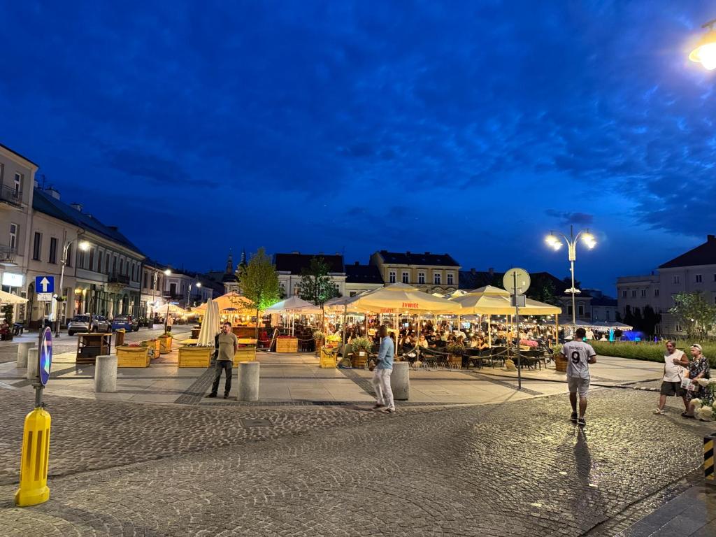 un grupo de personas caminando por la calle por la noche en Apartments -Gold Glass Jacuzzi & Sauna Rynek Centrum -Parking -fakvat, en Kielce