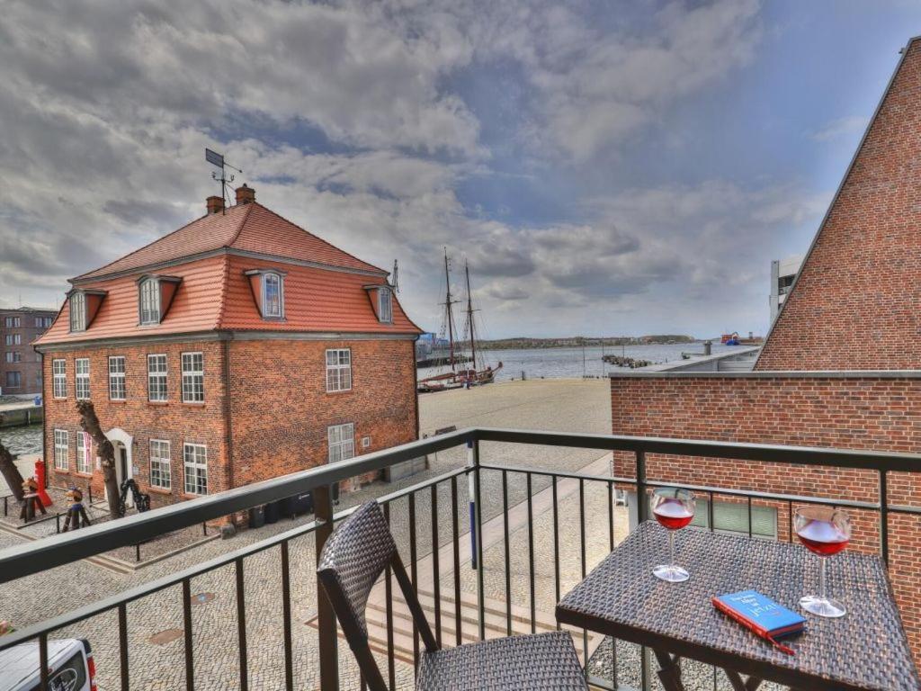 a balcony with a table with two glasses of wine at Ohlerich Speicher App_ 05 in Wismar