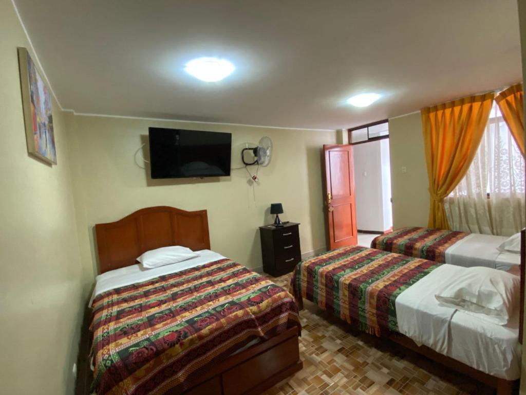 a bedroom with two beds and a flat screen tv at LA FAMILIA NASCA HOUSE in Nazca