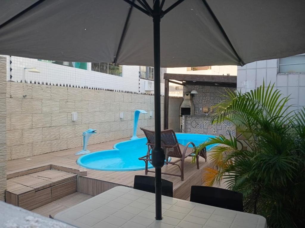 een patio met een parasol en een zwembad bij Apt amplo 3 quartos Manaíra in João Pessoa