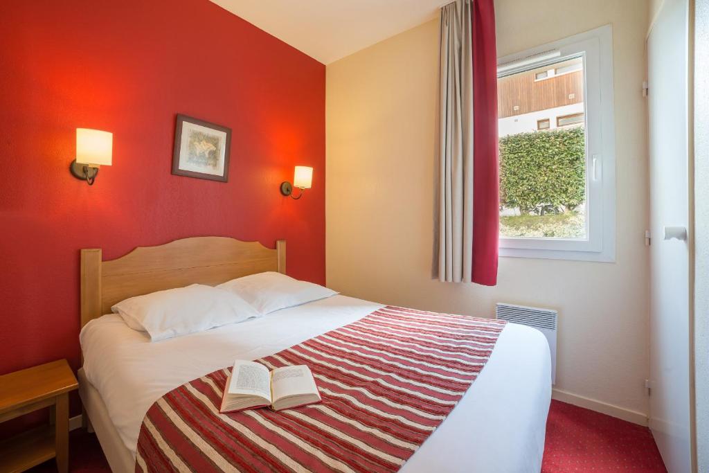 a bedroom with a bed with two books on it at Résidence Pierre & Vacances Les Rives de l'Aure in Saint-Lary-Soulan