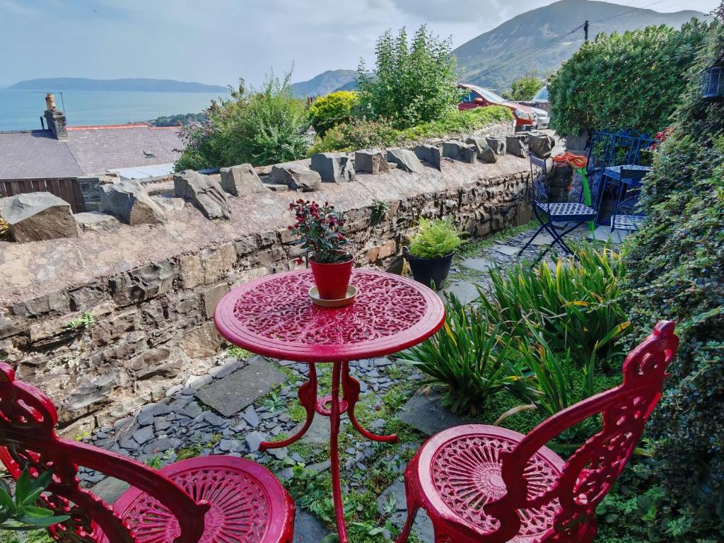 - une table et des chaises rouges sur la terrasse dans l'établissement Fantastic sea views at Century's old Alma's Cottage - Sleeps up to 8 guests, à Penmaen-mawr