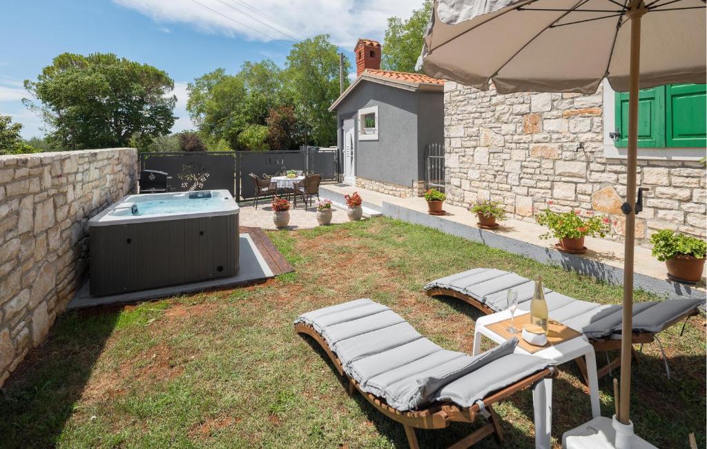 a backyard with a hot tub and chairs and an umbrella at Stunning Home In Umag With Wifi in Umag