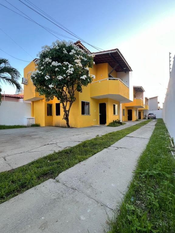 ein gelbes Haus mit einem Baum davor in der Unterkunft Beira Mar in Aracaju