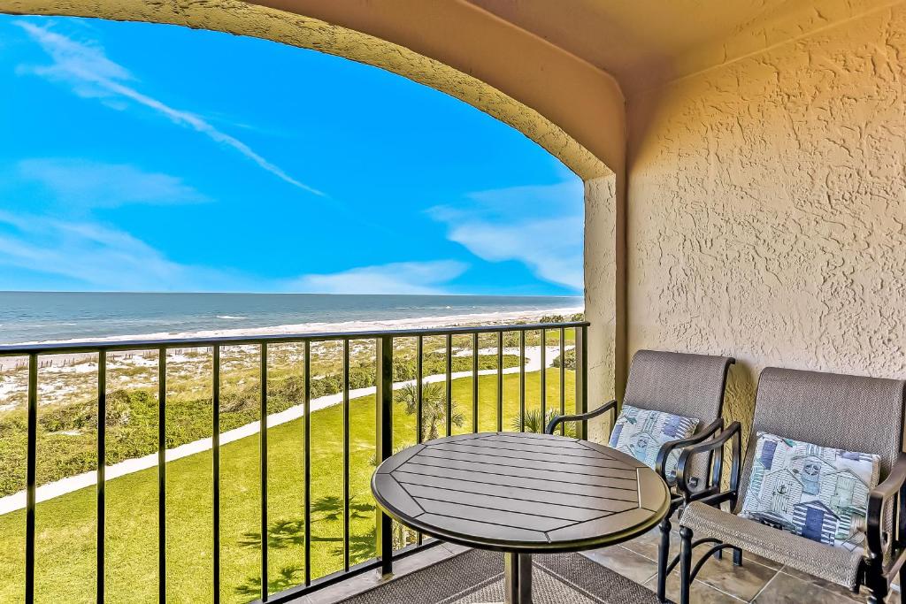 Turtle Dunes Ocean Front Studio Condo on Amelia Island Plantation في فرناندينا بيتش: شرفة مع طاولة وكراسي والمحيط