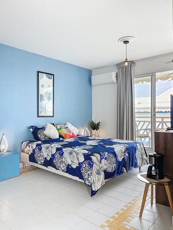 a blue bedroom with a bed and a blue wall at Studio Coin Du Bonheur in Saint-François
