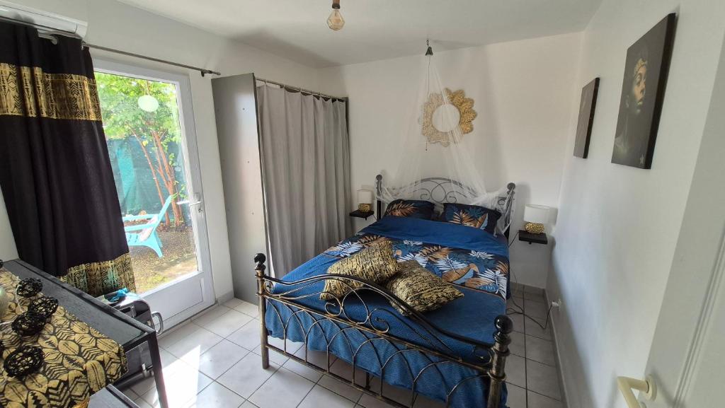 a bedroom with a bed with blue sheets and a window at TI BLUE plage à proximité in Les Trois-Îlets