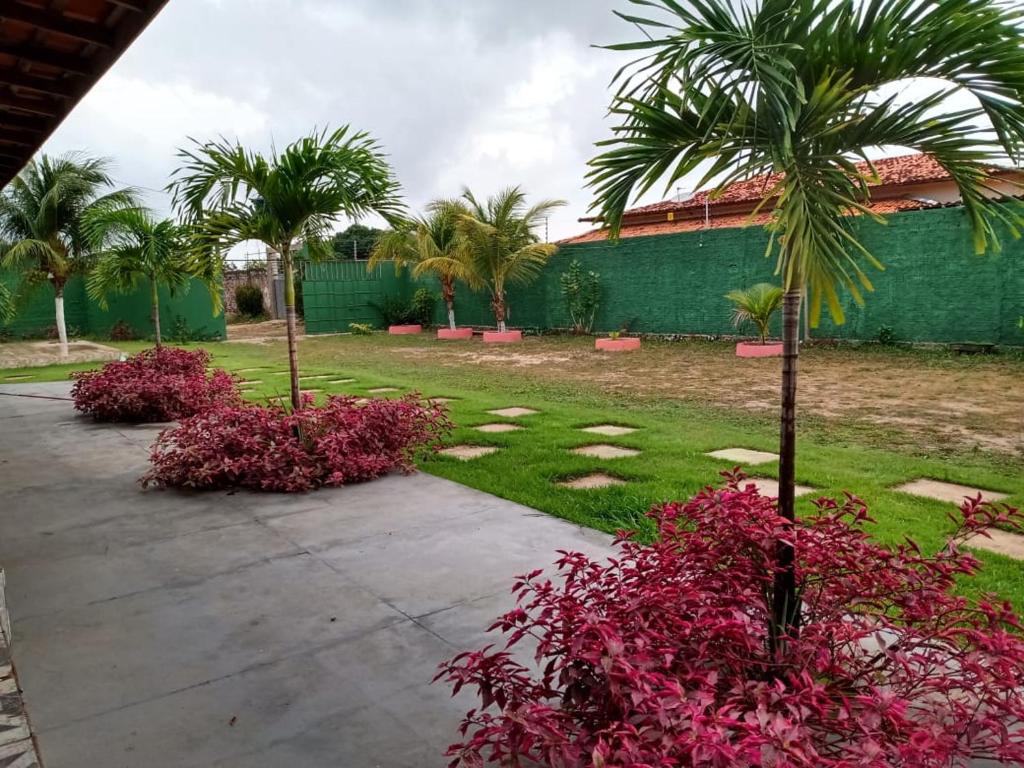 ein Garten mit Palmen und rosa Blumen vor einem Gebäude in der Unterkunft Chácara Recanto dos Poetas in Macajatuba