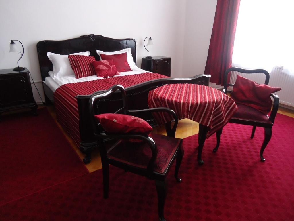 een slaapkamer met een bed met rode lakens en stoelen bij Hestia Lux in Cluj-Napoca