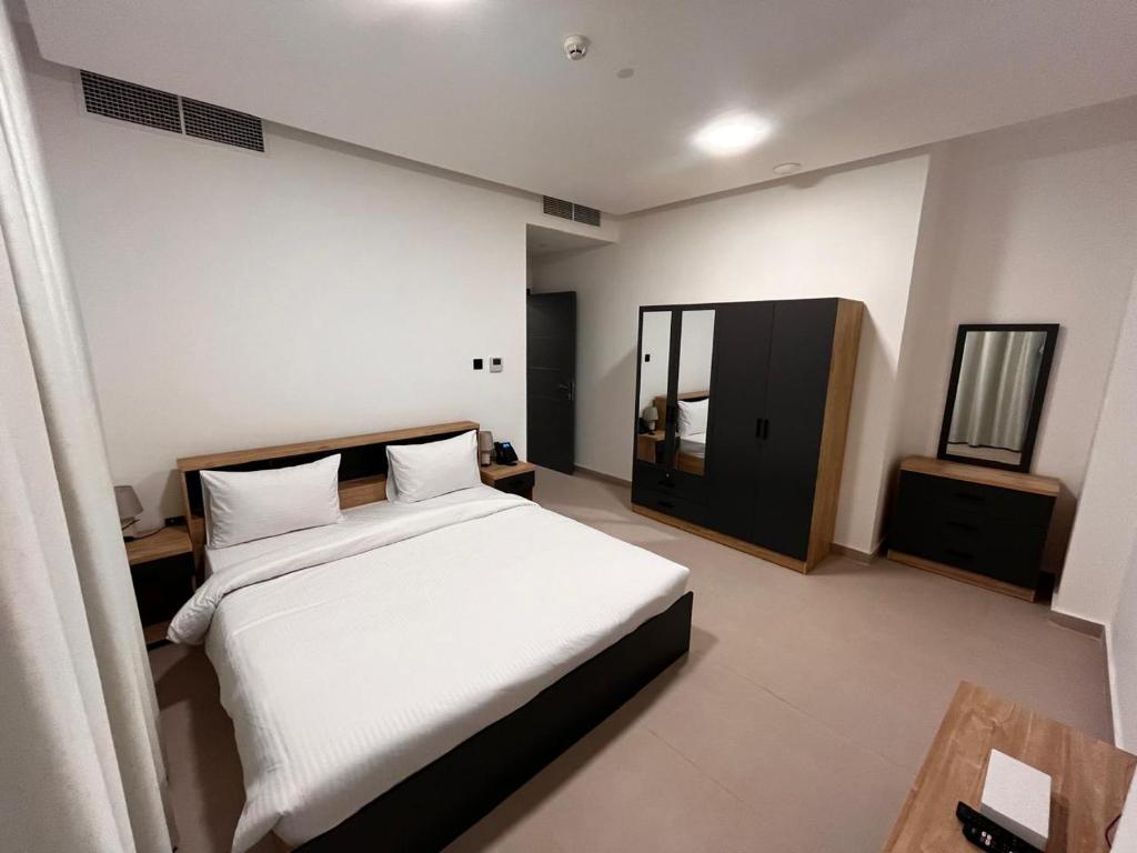 Un dormitorio con una gran cama blanca y un espejo. en Aryaf Hotel Apart Tabasum Group, en Ajman