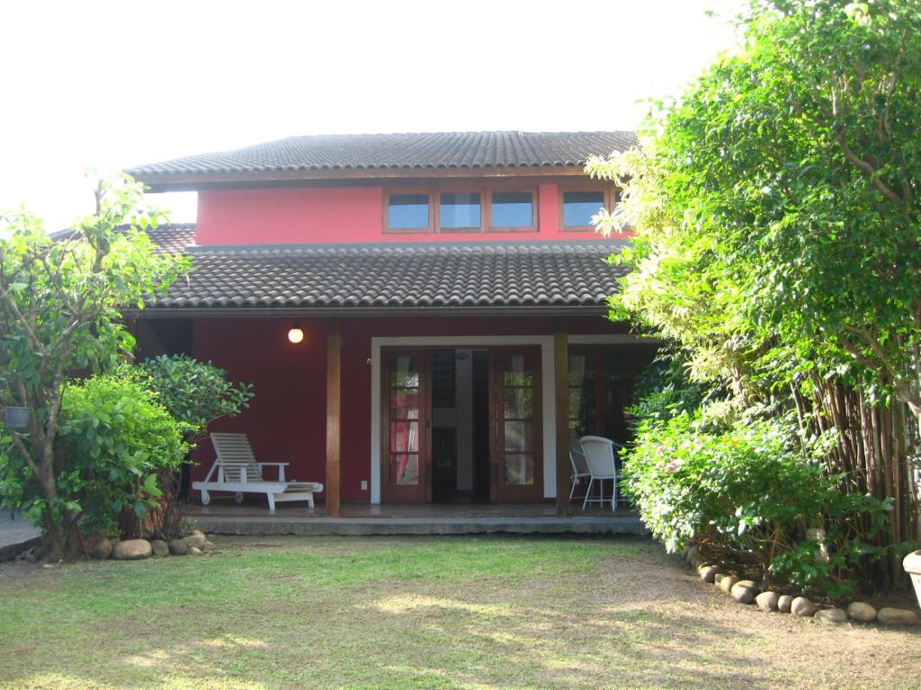 Casa roja con 2 sillas y porche en Casa do Sergio en Río de Janeiro