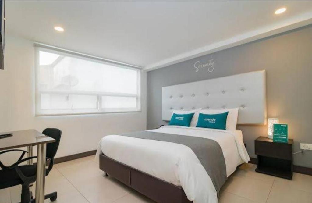 una camera da letto con un letto grande, una scrivania e una finestra di Serenity by noa hotels a Bogotá