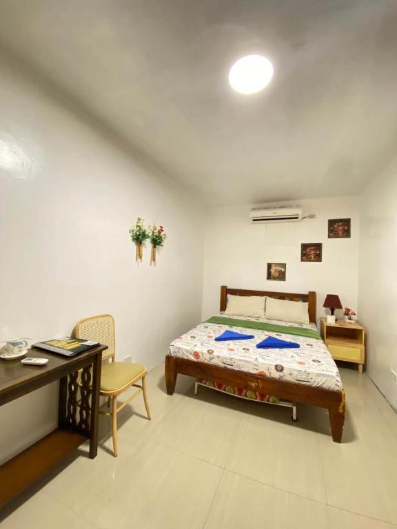 a bedroom with a bed and a desk and a table and chair at AlonaBeach Tourist Inn in Taporok