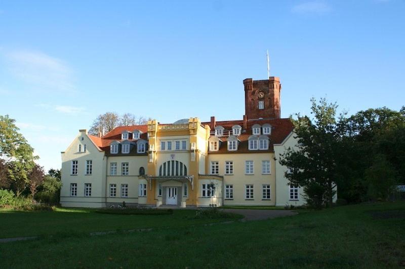 a large house with a clock tower on top of it at Schloss Lelkendorf, Fewo Hoppenrade in Lelkendorf