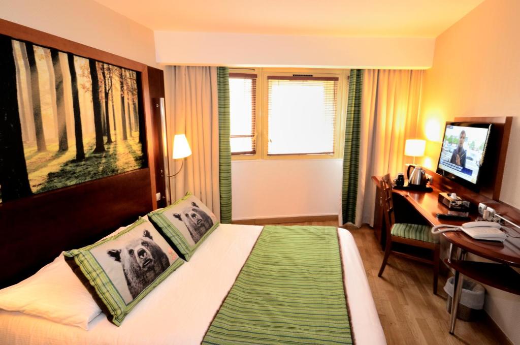 パリにあるグリーン ホテルズ コンフォート パリ 13のベッド、デスク、テレビが備わるホテルルームです。
