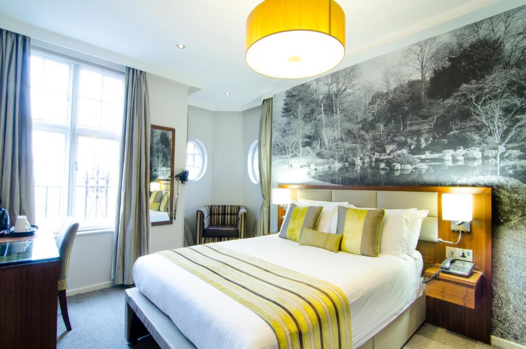 a hotel room with a bed and a desk and a window at Seraphine Kensington Olympia in London