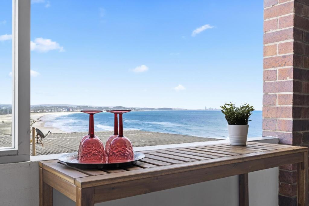 two pink vases on a wooden table with a view of the ocean at LOCATION, LOCATION! Walk to anywhere! in Gold Coast