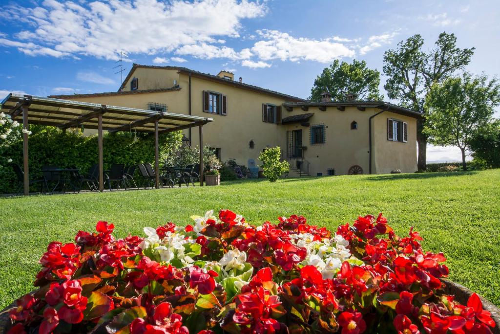 una cama de flores rojas y blancas delante de una casa en Il Nido di Gabbiano, en Scarperia