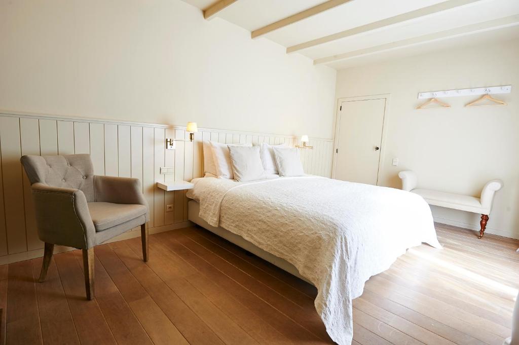a white bedroom with a bed and a chair at B&B Maryline in Antwerp