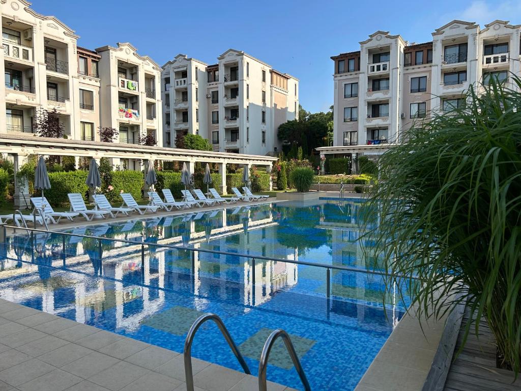 ein großer Pool mit weißen Stühlen und Gebäuden in der Unterkunft Дизайнерско студио ,Смокиня,Созопол,5 звезден затворен комплекс,4 басейна,1ва линия море in Sozopol