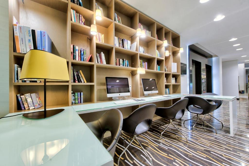 a library with chairs and a desk and bookshelves at Hotel Valentina in St. Julianʼs
