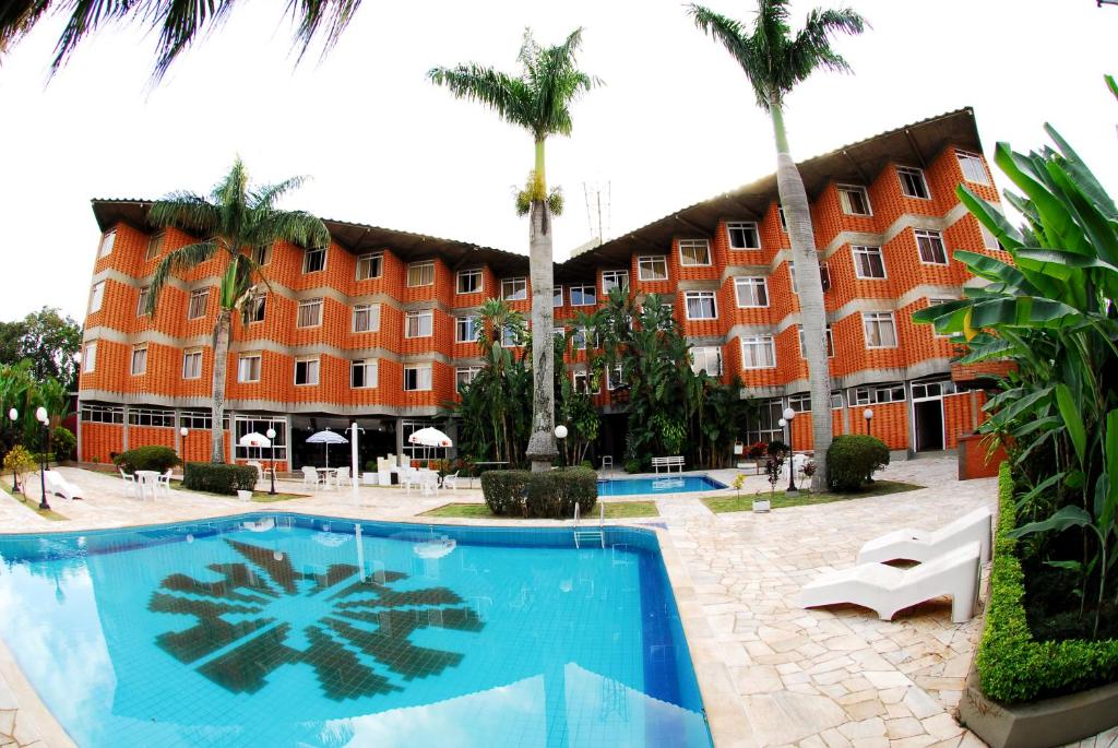 a hotel with a swimming pool in front of a building at Harbor Querência Hotel in Cascavel