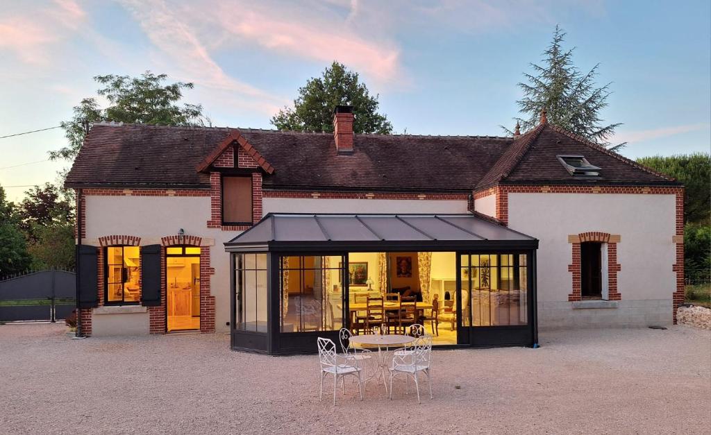 Una casa con un invernadero con mesa y sillas. en A l'Orée des Bois, calme et nature, en Villefranche-Sur-Cher