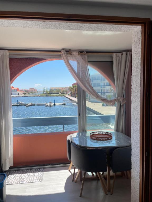 a window with a table and a view of the water at Appartement Marina in Le Barcarès