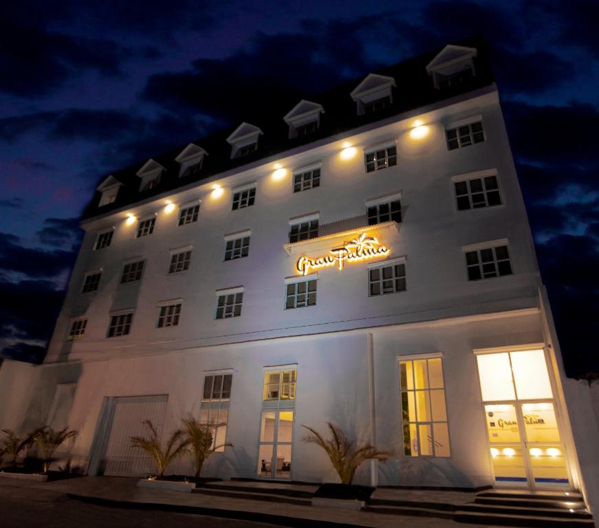 un gran edificio blanco con un cartel en él por la noche en Hotel Gran Palma Huancayo, en Huancayo