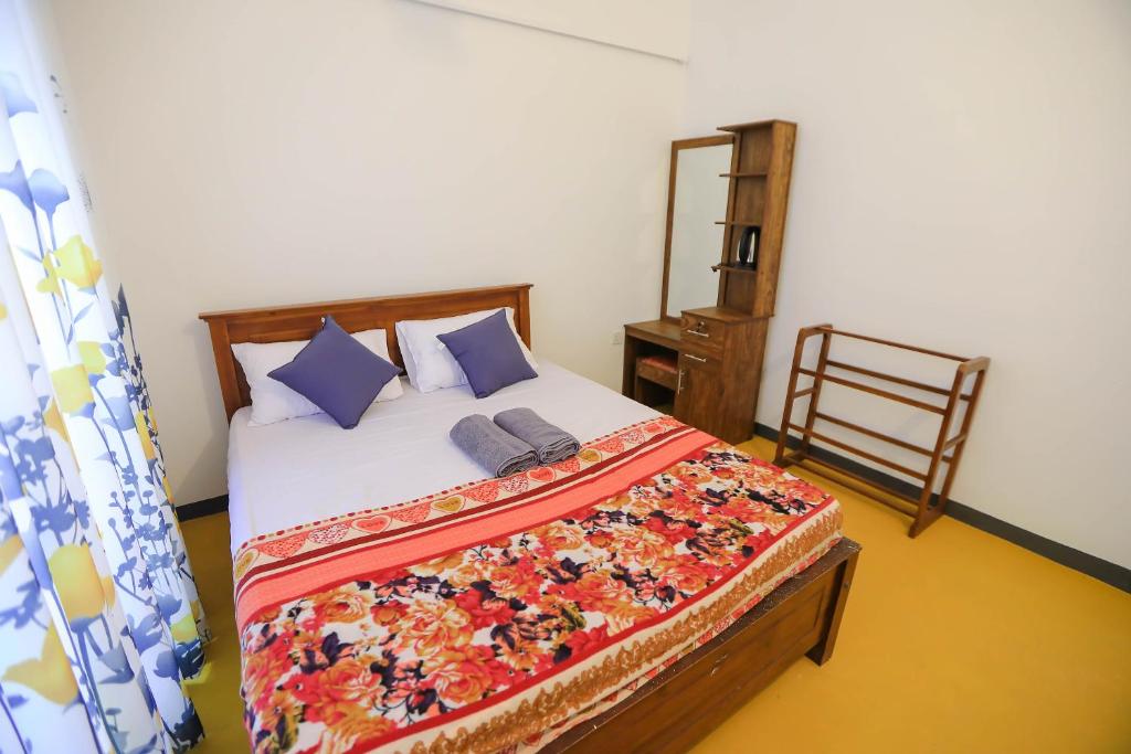 una camera da letto con un letto con cuscini blu e una sedia di VS BeachSide Resort a Negombo