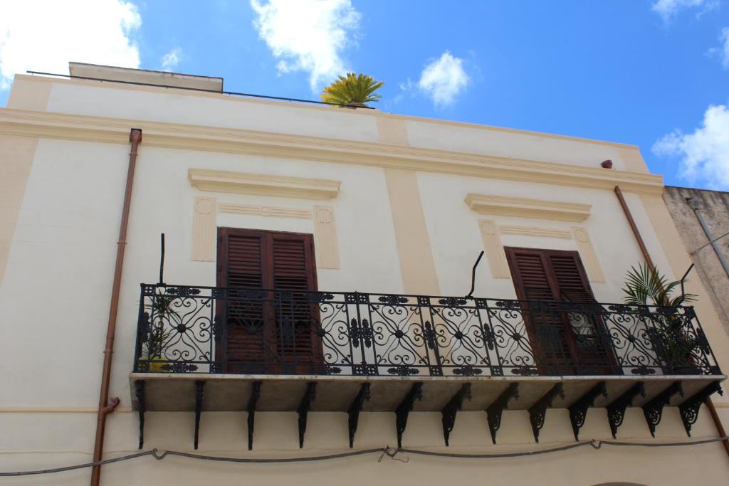 a white building with a balcony with brown shutters at Palazzo Taormina in Castellammare del Golfo