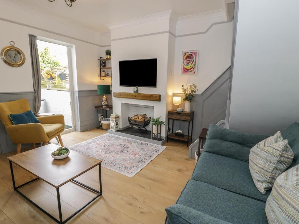 a living room with a blue couch and a fireplace at Mid Haven Cottage in Conwy