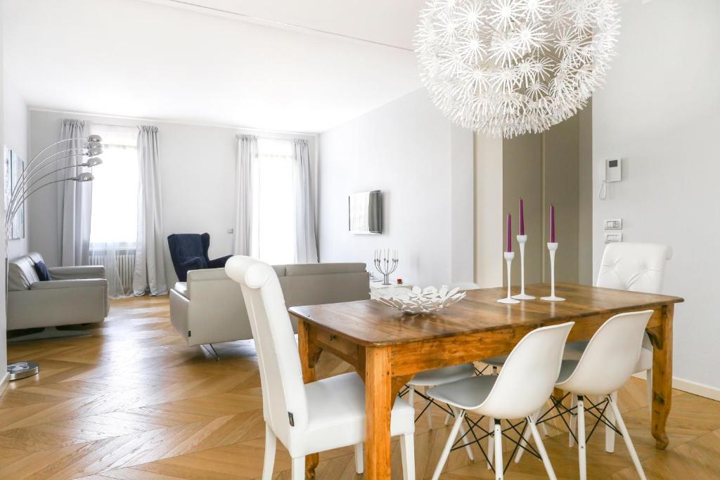 a dining room with a wooden table and white chairs at Riverside Apartment in Treviso