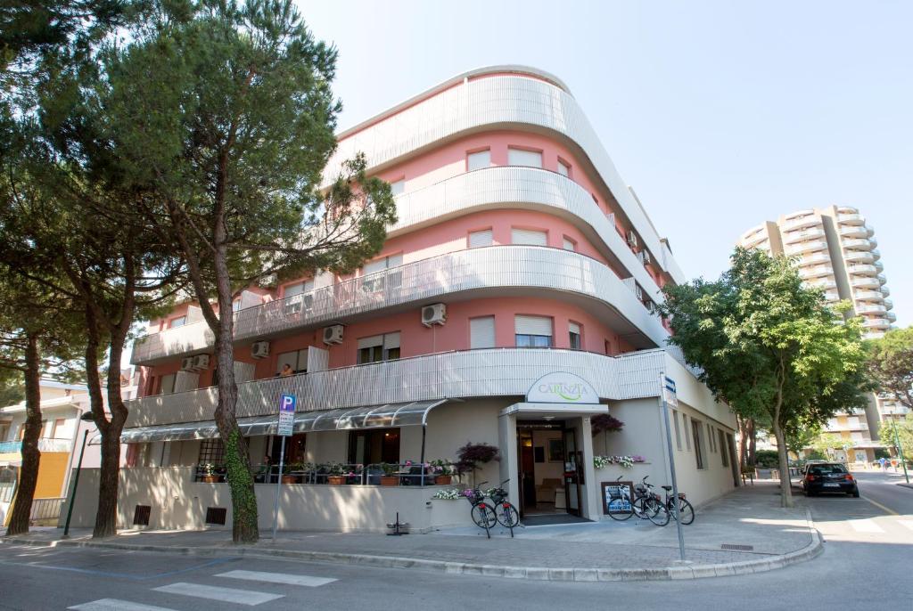 een roze gebouw met fietsen voor de deur bij Aparthotel Carinzia in Lignano Sabbiadoro