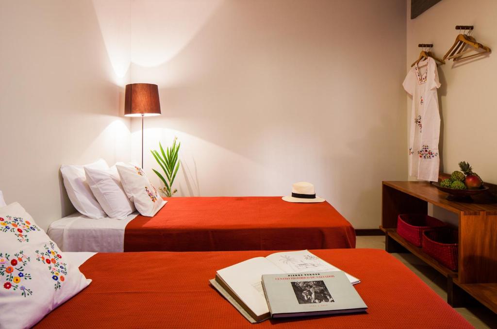 a hotel room with two beds and a book on a table at Pousada Casa da Vitória in Salvador