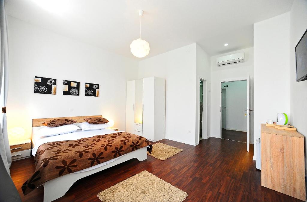 a white bedroom with a bed and a wooden floor at Valenti rooms in Split