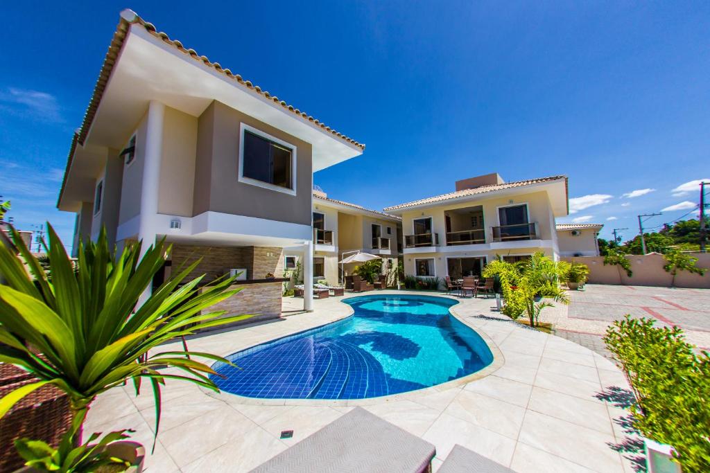 une villa avec une piscine en face d'une maison dans l'établissement Residencial Portinari LTDA, à Porto Seguro