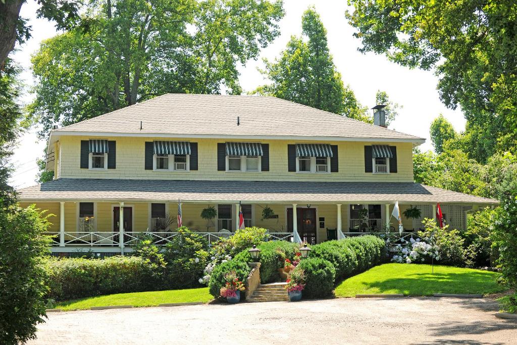 a yellow house with a porch and a yard at Orchard Inn in Saluda