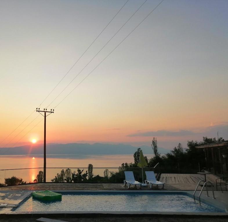 a swimming pool with two chairs and the sunset at CHRIS sopo in Elshani